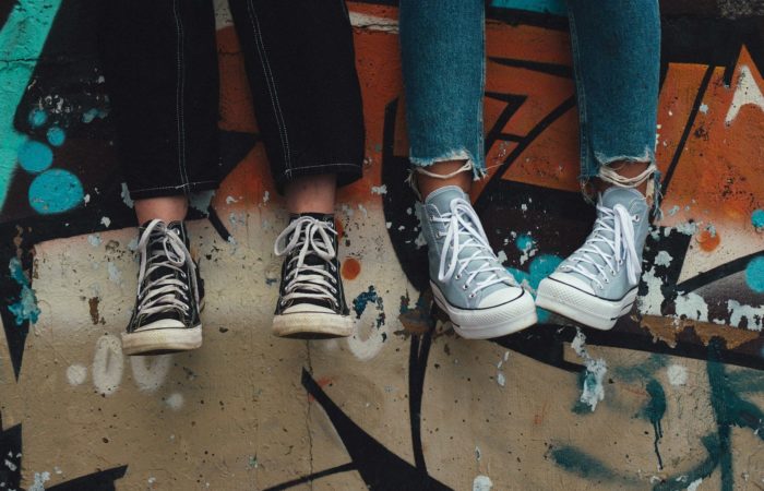 person in blue denim jeans wearing black and white converse all star high top sneakers